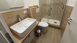 A modern bathroom with a large white sink, a toilet, and a glass-enclosed shower area. - Bart165 Luxury Rooms (Palermo)