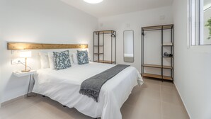 Ein Schlafzimmer mit Bett, Nachttischlampe, Kleiderschrank und Spiegel.