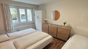 A bedroom with a bed, a dresser, a mirror, and a window with curtains. - Pearl Apartment (Interlaken)