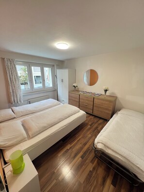 A bedroom with a bed, a dresser, a mirror, and a window with curtains. - Pearl Apartment (Interlaken)