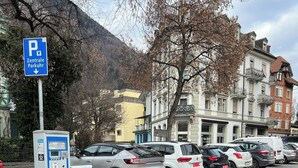 A parking area with a payment kiosk, bollards, and a sign for a central parking area. - Pearl Apartment (Interlaken)