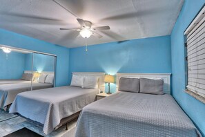 A hotel room with two beds, a ceiling fan, a large mirror, and a window with blinds. - Holiday Villas III #209 (Indian Shores)