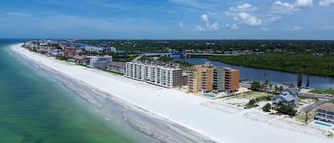 Una zona costera con una extensa playa arenosa, un puerto deportivo y varios edificios de varios pisos.