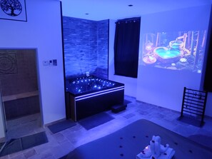 A modern spa room with a heated stone bath, a projection screen displaying a nature scene, and a relaxation area with a massage table. - Hammam & Balneo Suite, air-conditioned, with a private outdoor area (Roquevaire)