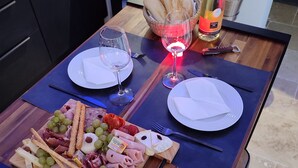 A dining table set with a charcuterie board, two wine glasses, a bottle of champagne, and a red rose. - Hammam & balneo suite, air-conditioned, with private outdoor area  (Roquevaire)