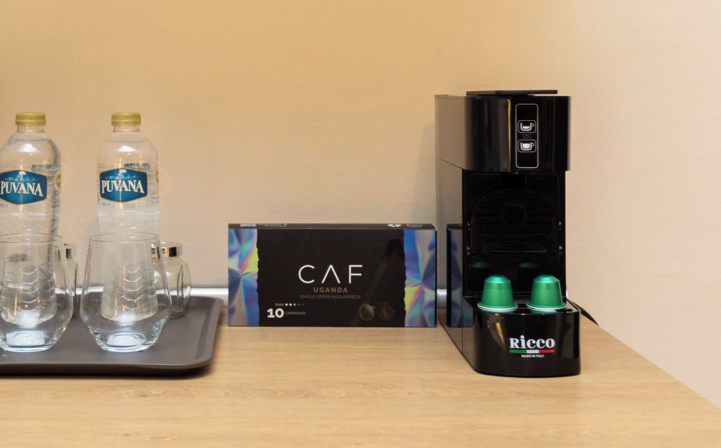 Eine Kaffeemaschine, zwei Wasserflaschen und eine mit 'CAF' beschriftete Kiste auf einem Tisch.