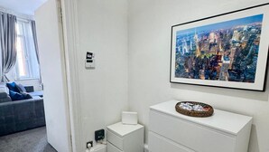 A hotel room with a cityscape view, a white dresser, a small bedside table, and a window with curtains. - Sleeps4- Sofabed- 5mintocitycentre- Glasgowgreen (Glasgow)