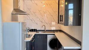 A compact kitchen with a built-in washing machine, a sink, and a stove. - Sleeps4- Sofabed- 5mintocitycentre- Glasgowgreen (Glasgow)