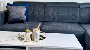 A modern living room with a dark grey sofa, a white coffee table, and a small potted plant. - Sleeps4- Sofabed- 5mintocitycentre- Glasgowgreen (Glasgow)