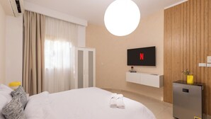 Ein Hotelzimmer mit einem Bett, einem an der Wand befestigten Fernseher, einem kleinen Kühlschrank und einer Wandverkleidung aus Holz.