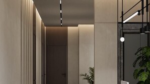 Un passadís modern i minimalista amb una taquilla d'hostaleria, una planta en test i una porta al final.