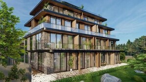 Un edifici modern d'àmbit elevat amb grans finestres i balcons, envoltat de vegetació.