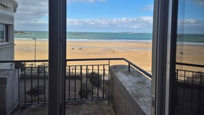A balcony with a view of a sandy beach and the sea.