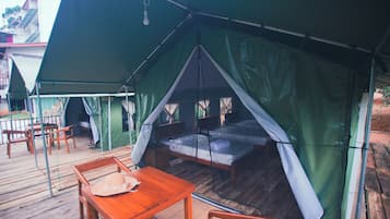 Una carpa con una cama, una mesa y sillas sobre una terraza de madera.