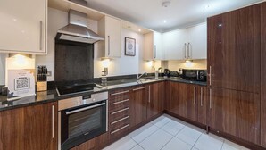 Een moderne keuken met donkerhouten kastjes, roestvrijstalen apparatuur en een granieten aanrecht.
