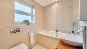 Een moderne badkamer met een bad, wastafel en toilet.