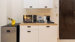 A compact kitchenette with a microwave, coffee maker, and water bottles. - Host Prime Boutique Hotel 01 (New Cairo)