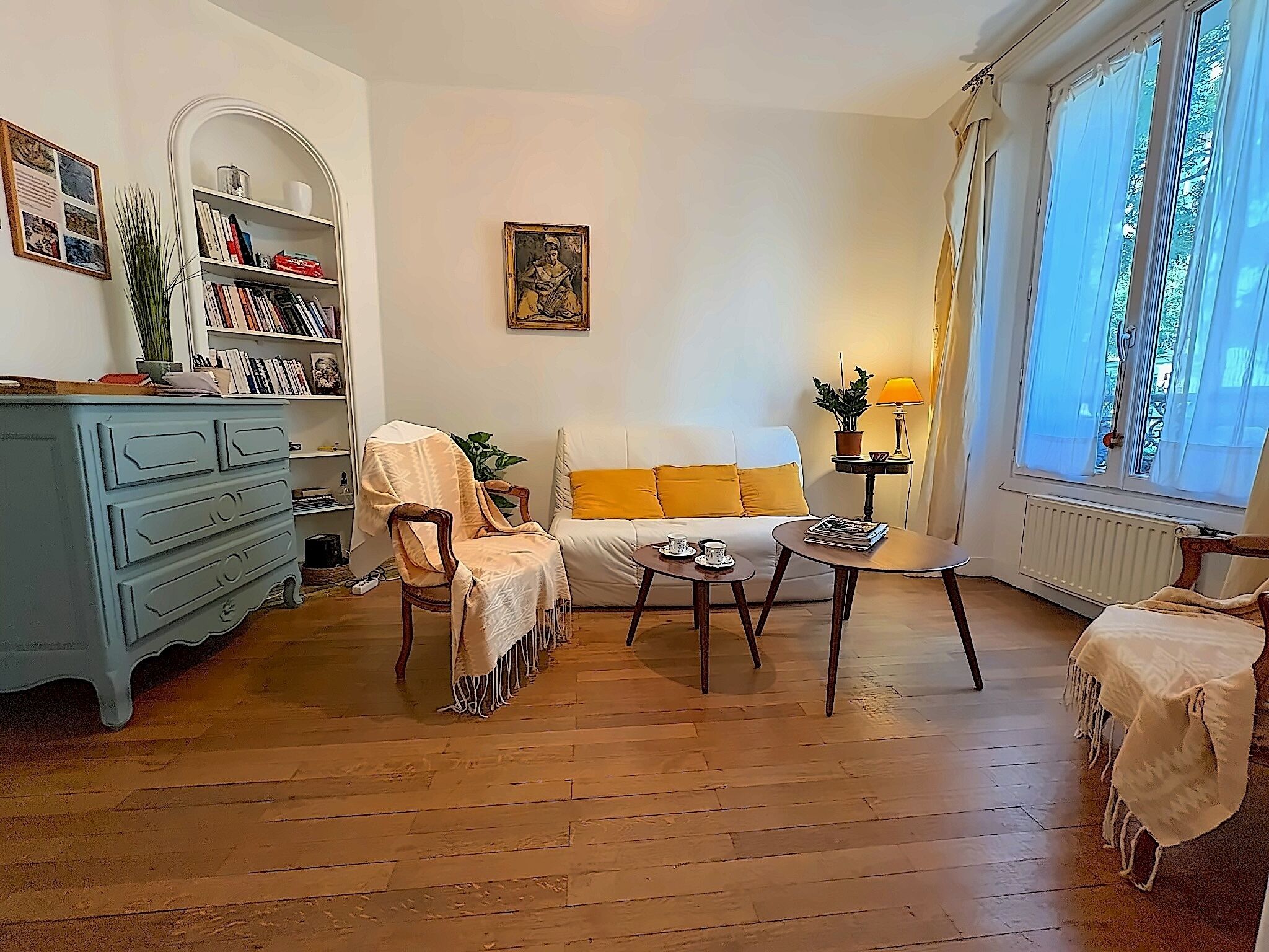 A living room with a sofa, armchairs, a coffee table, and a bookshelf.
