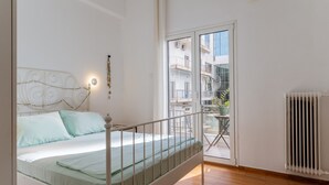 A bedroom with a bed, a balcony with a table and chairs, and a radiator. - Apartment 'Unique Stays in Athens' with Shared Terrace, Wi-Fi and Air Conditioning (Kallithea)