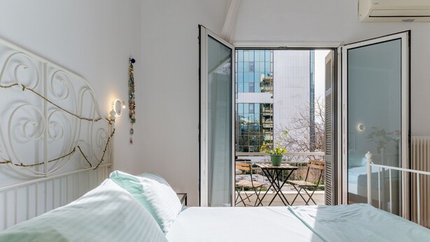 A bedroom with a bed, a balcony with a table and chairs, and a view of buildings. - Apartment 'Unique Stays in Athens' with Shared Terrace, Wi-Fi and Air Conditioning (Kallithea)