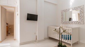A white room with a crib, a television, and a mirror on the wall. - Apartment 'Unique Stays in Athens' with Shared Terrace, Wi-Fi and Air Conditioning (Kallithea)