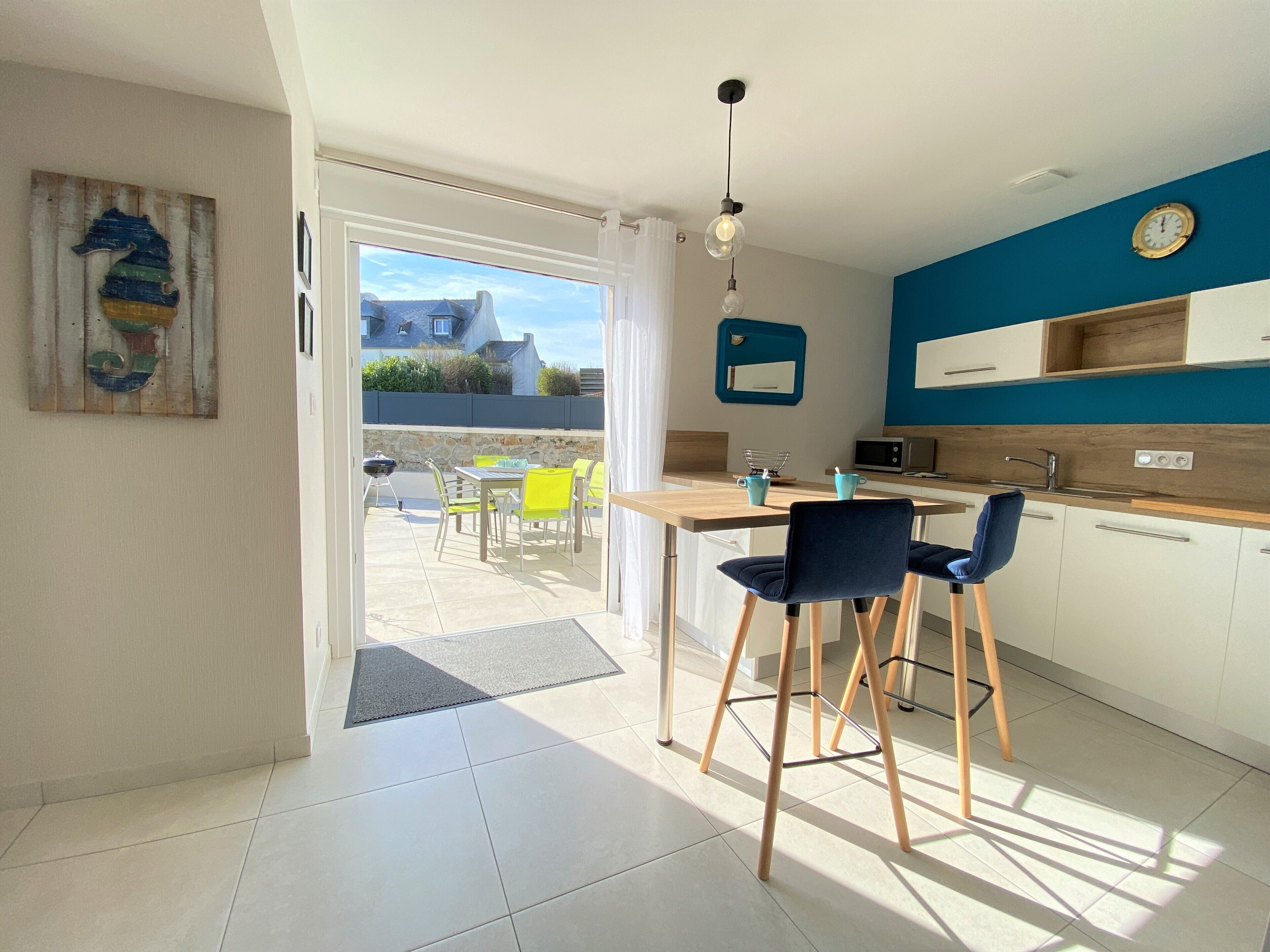 A modern kitchen with a dining area, a view to the outside, and a blue accent wall.