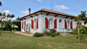 Un bâtiment blanc avec des volets rouges et un toit recouvert de tuiles.