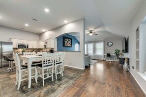 A modern kitchen with white cabinetry, a dining area with a white table and chairs, and a blue accent wall. - 3BD Home  Garage  HWY 360  Grand Prairie (GP020) (Grand Prairie)