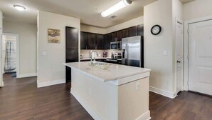 A modern kitchen with dark cabinets, stainless steel appliances, and a white island. - 3BD  Pool Table Dallas Dallas DAL212 (Dallas)