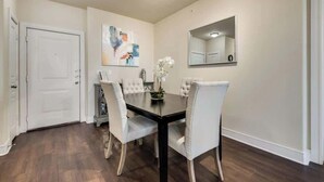 A dining area with a black table and white chairs, a painting on the wall, and a mirror above the table. - 3BD  Pool Table Dallas Dallas DAL212 (Dallas)