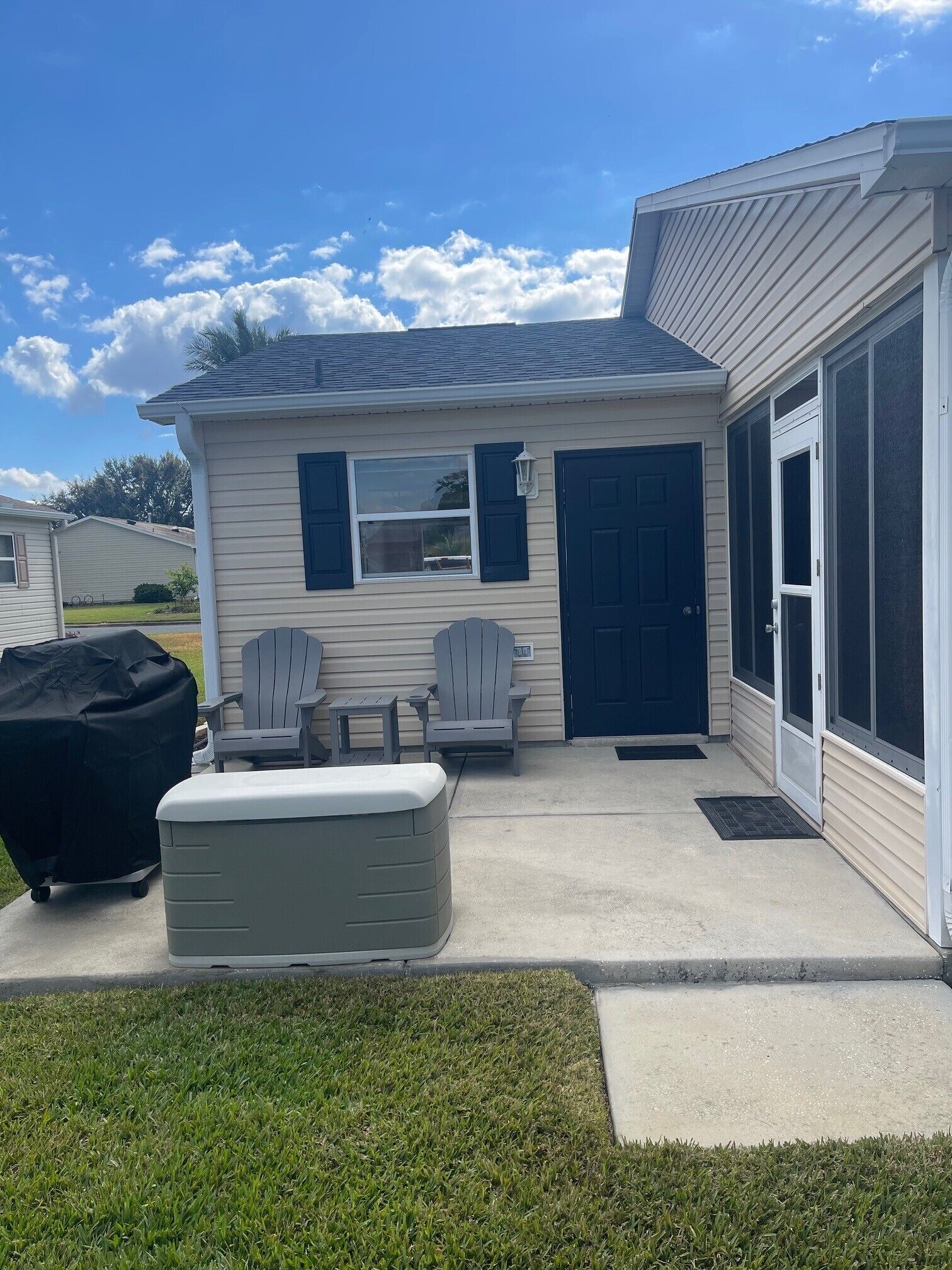Una pequeña casa con una parrilla techada, dos sillas Adirondack y un jacuzzi.