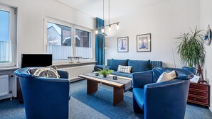A living room with a sofa, armchairs, a coffee table, and a television.