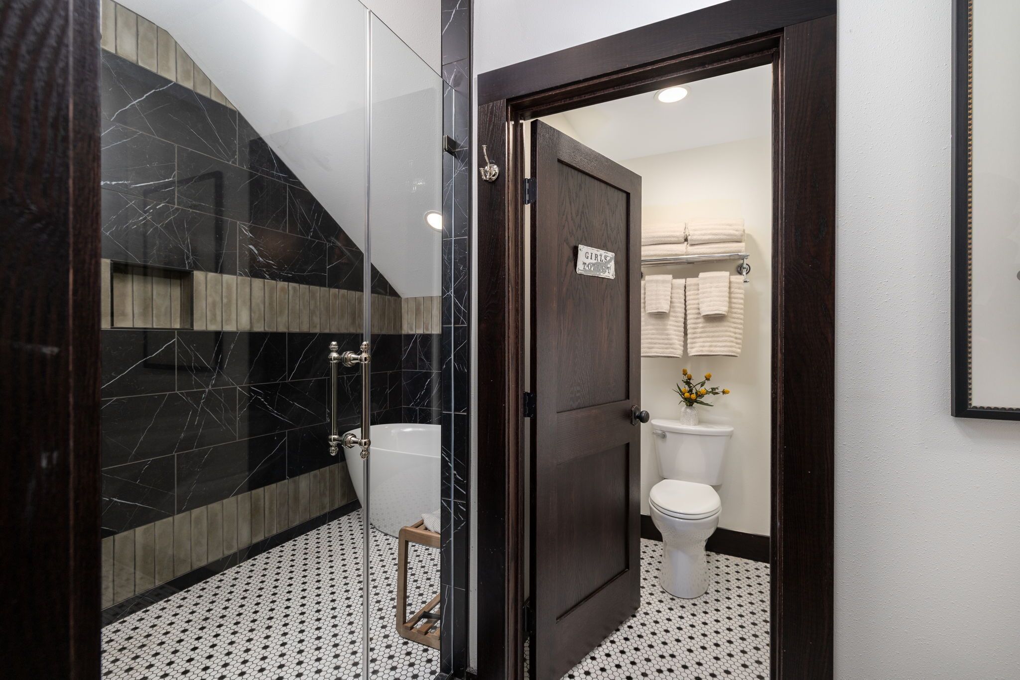 Un baño moderno con ducha de vidrio, inodoro blanco y puerta de madera.