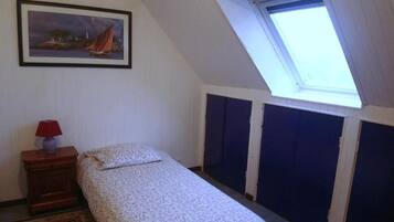 Een slaapkamer met een bed, nachtkastje, lamp, schilderij en dakraam.