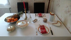 Mesa lista para comer, con platos, cubiertos, un cuenco de fruta y una vela.