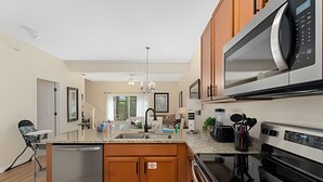 Cozinha moderna com ilha central, eletrodomésticos de aço inoxidável, armários de madeira e uma janela grande que proporciona iluminação natural.