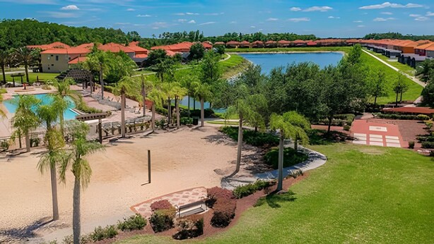 Um resort com piscina, palmeiras e uma grande extensão de água.