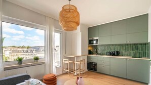 A modern apartment with a kitchen, dining area, and a large window with a city view. - Studio terrace in the center of town (Luxembourg)