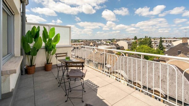A balcony with potted plants, a table, and chairs. - Studio terrace in the center of town (Luxembourg)