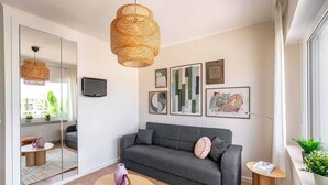 A modern living room with a grey sofa, a round wooden coffee table, and a large woven pendant light. - Studio terrace in the center of town (Luxembourg)