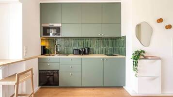 A compact kitchen with teal cabinets, a built-in oven, and a sink.