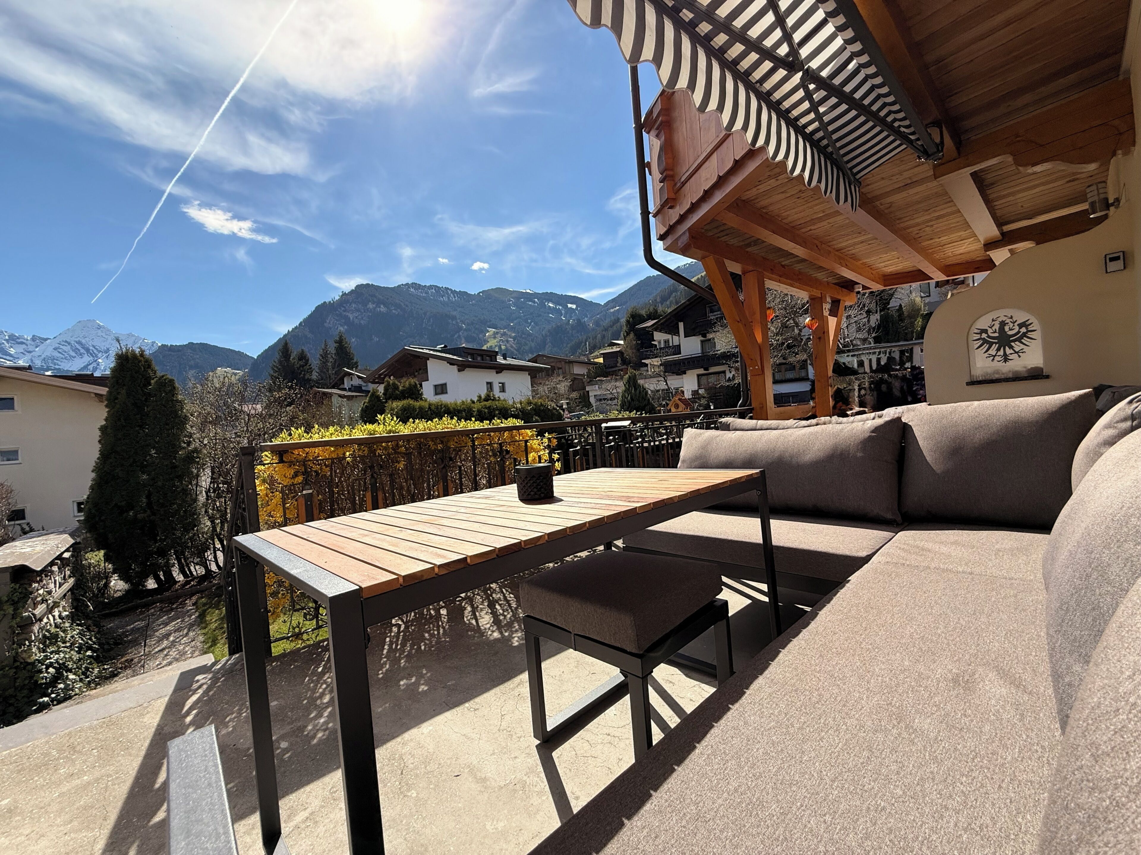 Une terrasse avec une table et un canapé en bois, une vue sur les montagnes et une architecture traditionnelle.
