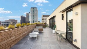 Une terrasse sur le toit avec des sièges extérieurs, un jardinier en bois et une vue panoramique sur la ville.