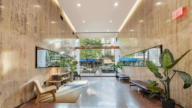 Un hall d’entrée moderne avec un mur en verre, des espaces de détente et des plantes en pot.