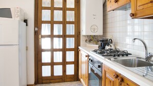 A kitchen with wooden cabinets, a white refrigerator, a stove, and a sink. - Lòbia in via Parrochiale - app. Legno (P2) (Barzio)