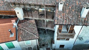An aerial view of a historic building with a tiled roof, a wooden balcony, and a small window. - Lòbia in via Parrochiale - app. Legno (P2) (Barzio)