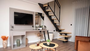 A modern living room with a flat-screen TV, a staircase, a coffee table, and a sofa. - Villa Garden Boutique Hotel Tirana (Tirana)