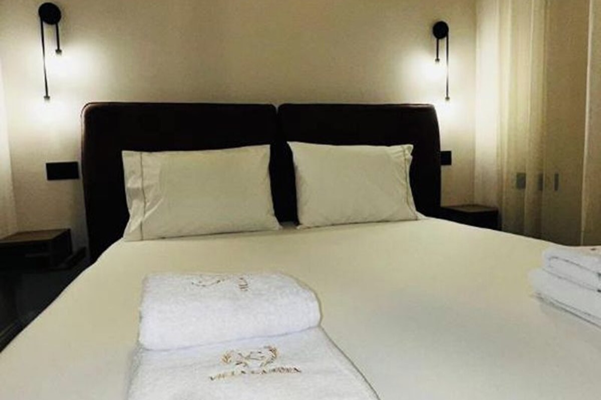 A neatly made bed with white linens and a folded towel.