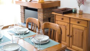 A dining table set with plates, glasses, and cutlery, wooden chairs, and a wooden cabinet with drawers. - Lòbia in via Parrochiale - app. Pietra (P1) (Barzio)