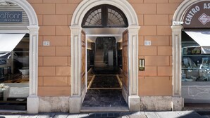 Entrada de un edificio con una escalera de mármol que lleva a un rellano en el segundo piso.